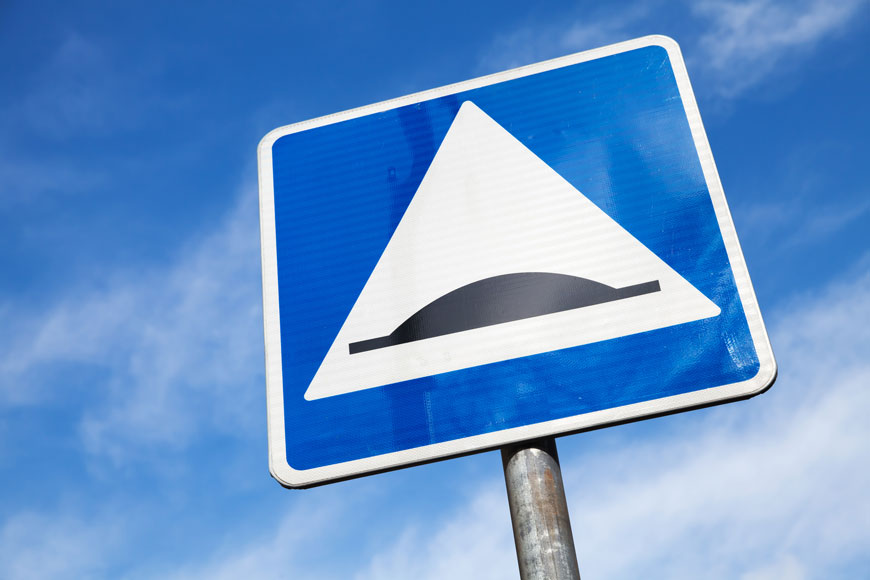 square speed bump road sign in front of a blue sky