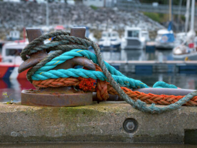 A series of colorful hawsers are draped over a staghorn bollard on a Scottish marina