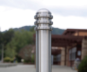 A stainless steel bollard is decorated with three rings below a curving cap