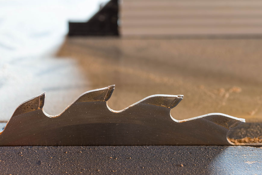 A close-up of a jagged toothed table saw shows two different metals on the teeth.
