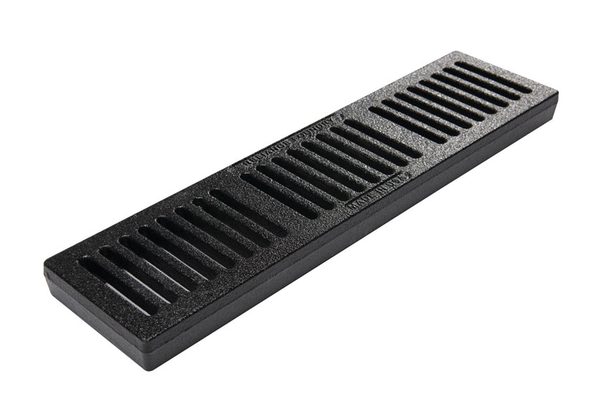 A simple black-painted trench grate with slots across its width sits on a white background