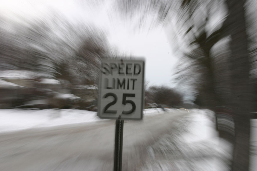 A sign says SPEED LIMIT 25, black on a white background