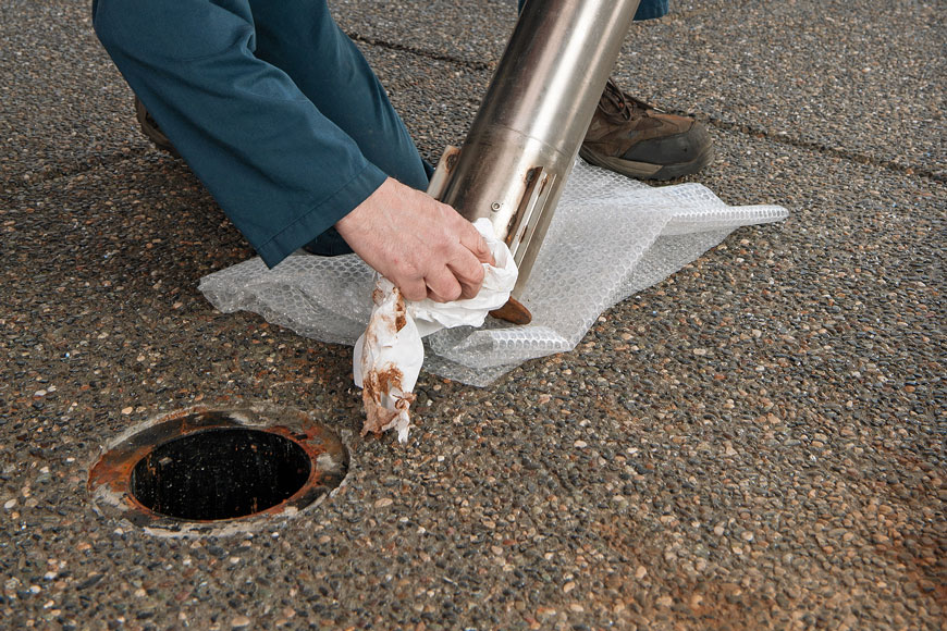 Retractable bollard in a parking lot being prepared for winter with surface rust on receiver