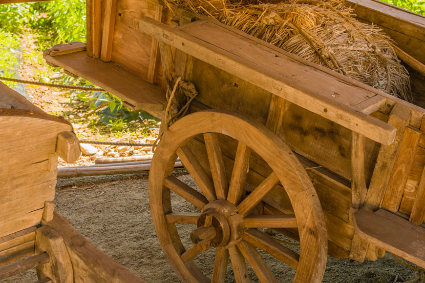 A two-wheel haycart made entirely of wood has wooden spoked wheels